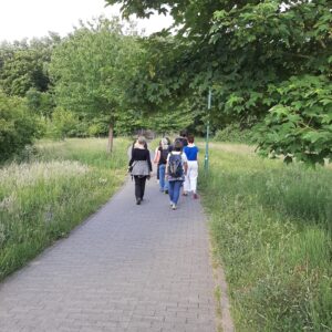 Eine Gruppe Menschen geht in Darmstadt achtsam zwischen Wiese und Bäumen.